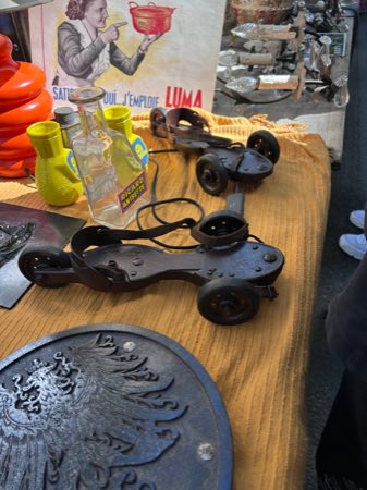 Antique metal roller skates with leather ankle straps on a market table