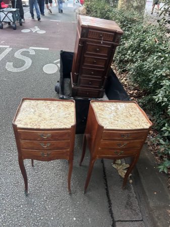 Marble-top nightstands and a tall marquetry chest of drawers on a street