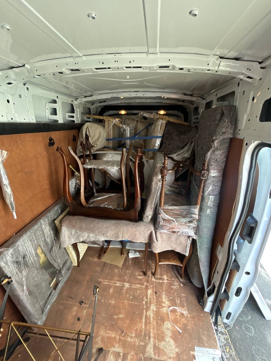 Van interior loaded and strapped down with chairs and wrapped furniture bought at a French flea market