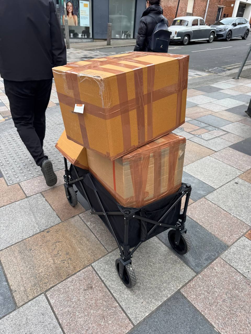 Two oversized boxes on a foldable wheel cart on a London street — at the absolute size limit of standard parcel couriers